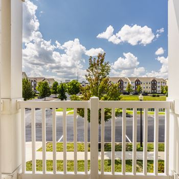 A white fence in front of a road with apartment buildings in the background.